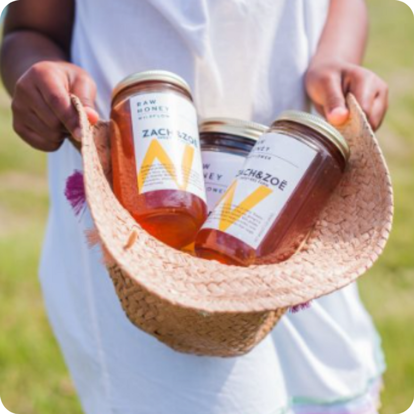 girl holding jars of honey in sunhat